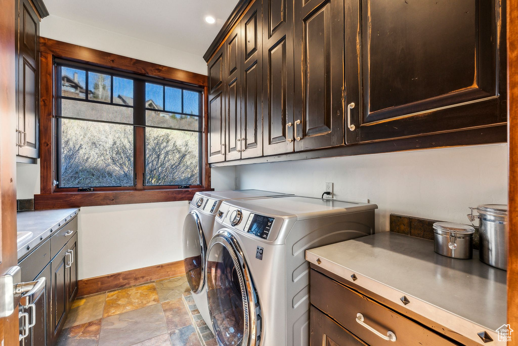 Washroom with baseboards, washing machine and dryer, stone finish flooring, and cabinet space