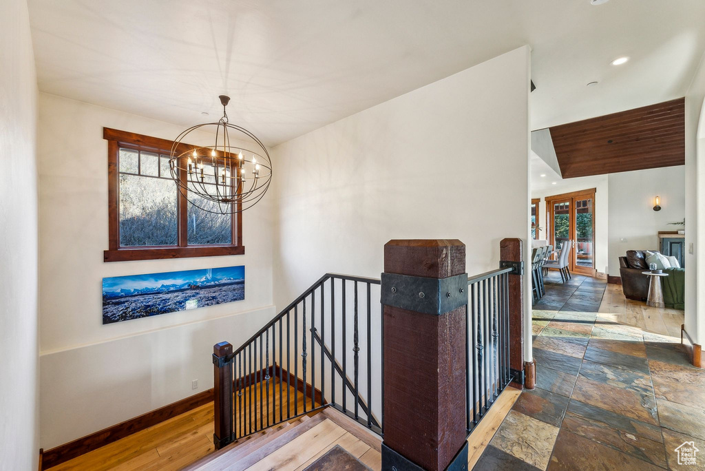 Stairs with baseboards, recessed lighting, stone tile flooring, and a notable chandelier