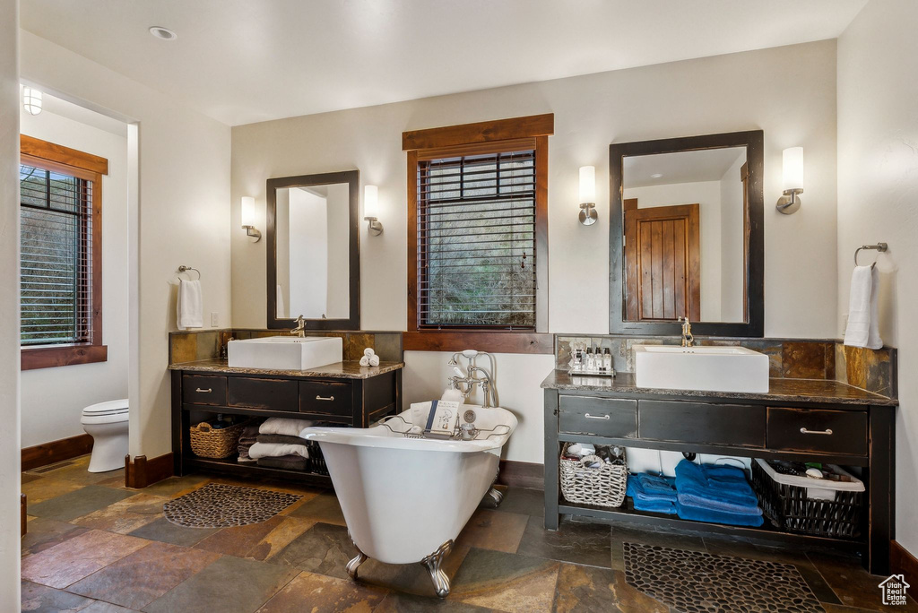 Bathroom with a sink, baseboards, and stone tile floors