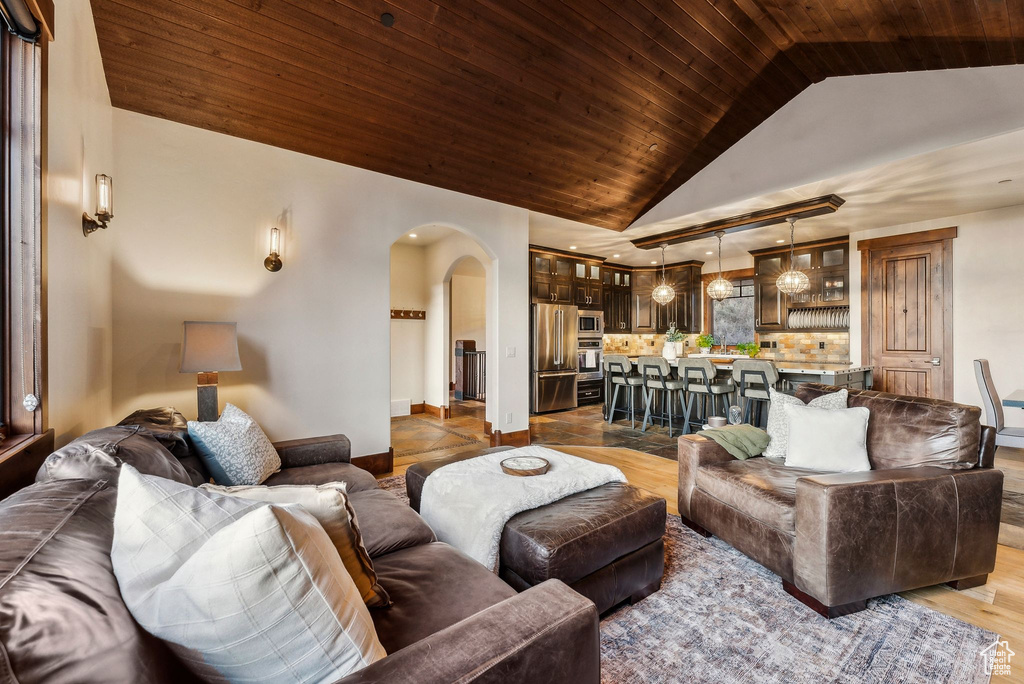 Living area featuring arched walkways, wood finished floors, wooden ceiling, baseboards, and lofted ceiling