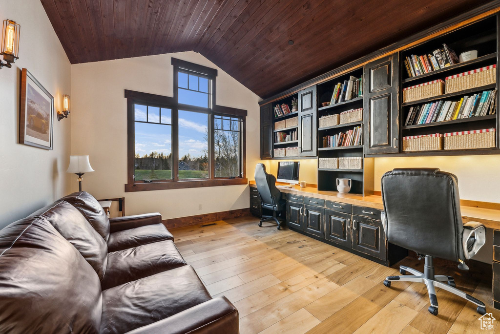 Office space with vaulted ceiling, built in desk, wooden ceiling, baseboards, and light wood-style flooring