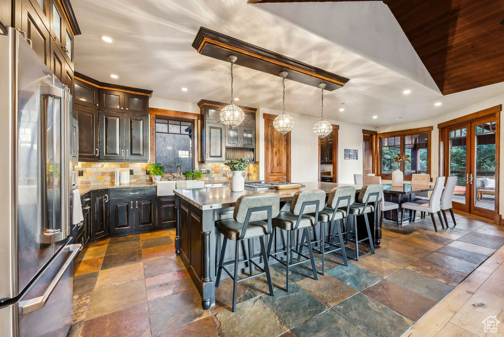 Kitchen with high end refrigerator, a center island, decorative backsplash, and stone tile floors