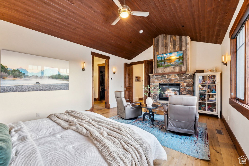 Bedroom featuring a stone fireplace, wooden ceiling, wood finished floors, lofted ceiling, and visible vents
