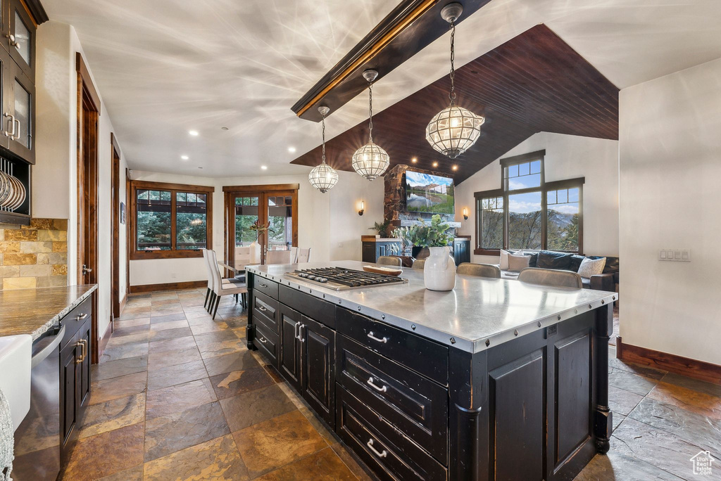 Kitchen featuring dark cabinetry, stone tile floors, baseboards, and a chandelier