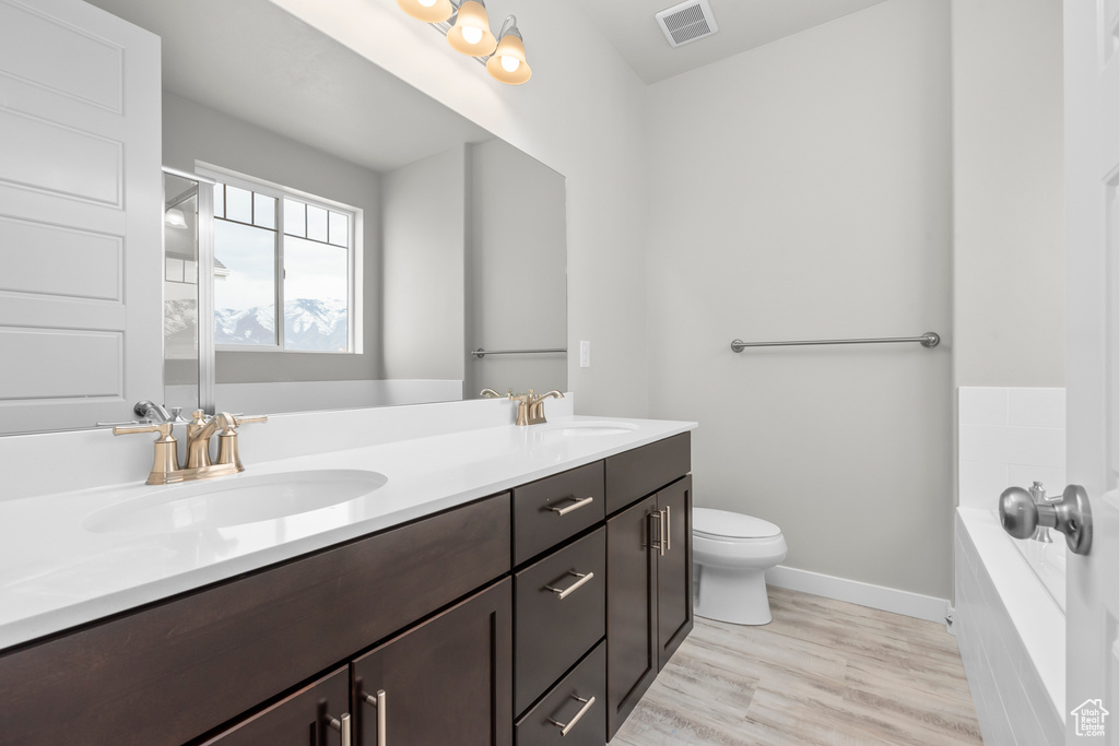 Bathroom featuring a sink, a bath, double vanity, and visible vents