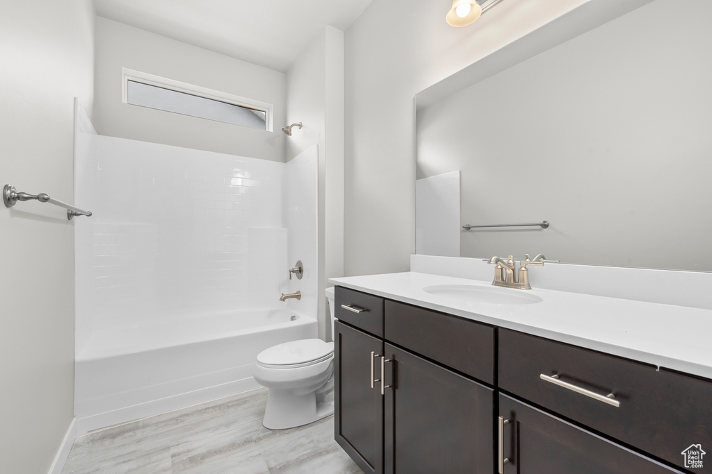 Bathroom with vanity, toilet, wood finished floors, and shower / tub combination
