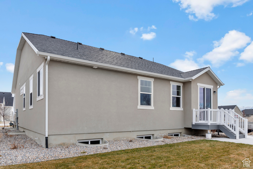 Back of property with a lawn and stucco siding