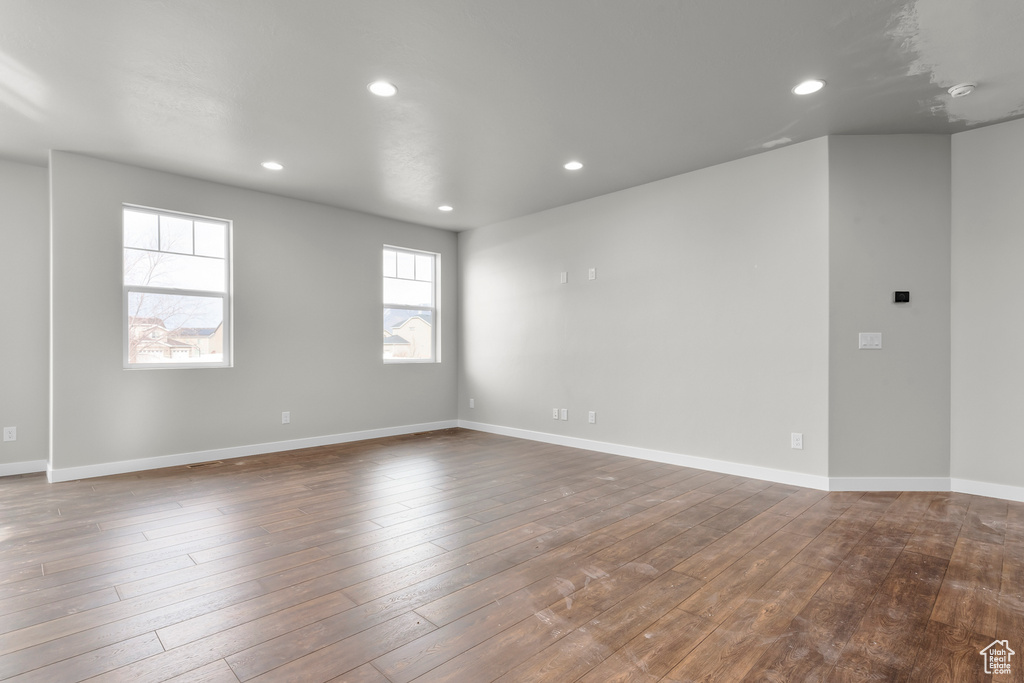 Empty room with recessed lighting, dark wood-style flooring, and baseboards