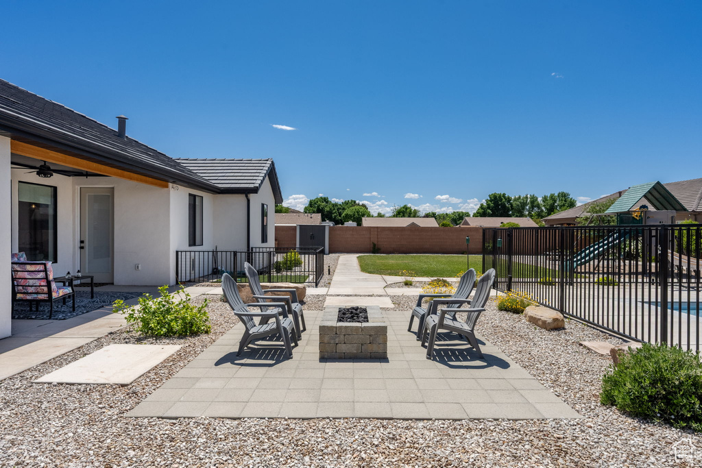 View of patio with a fenced backyard, a ceiling fan, and an outdoor fire pit