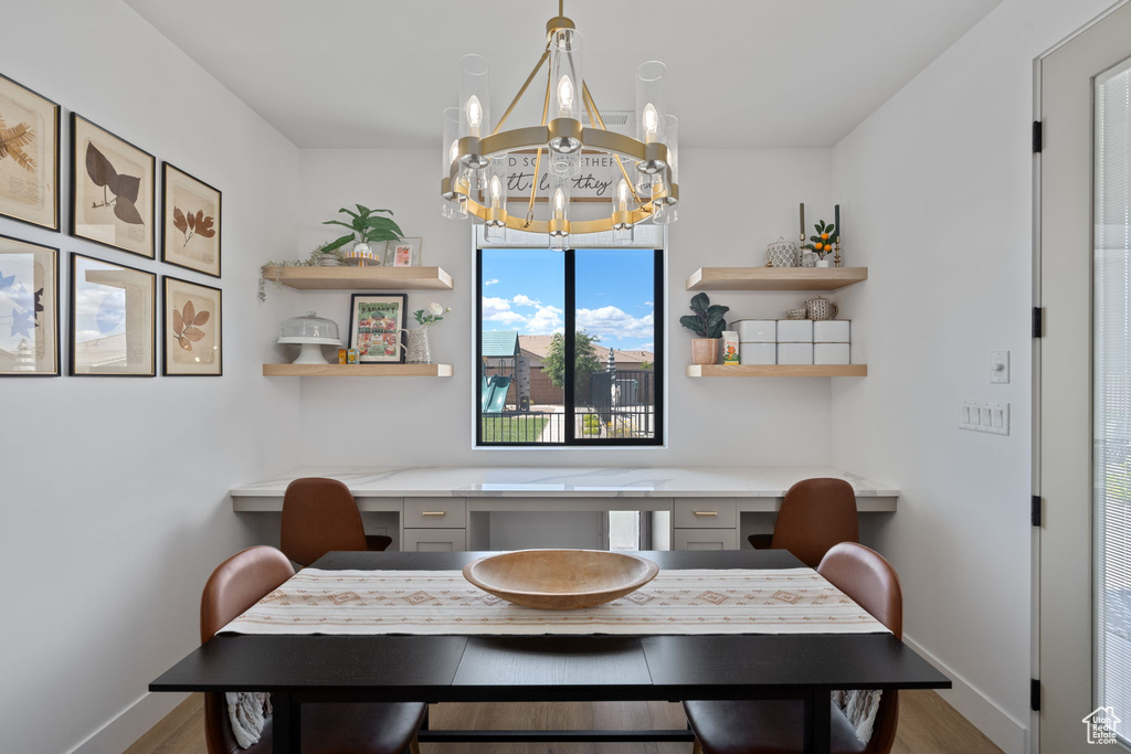 Dining space featuring baseboards, an inviting chandelier, wood finished floors, and built in study area