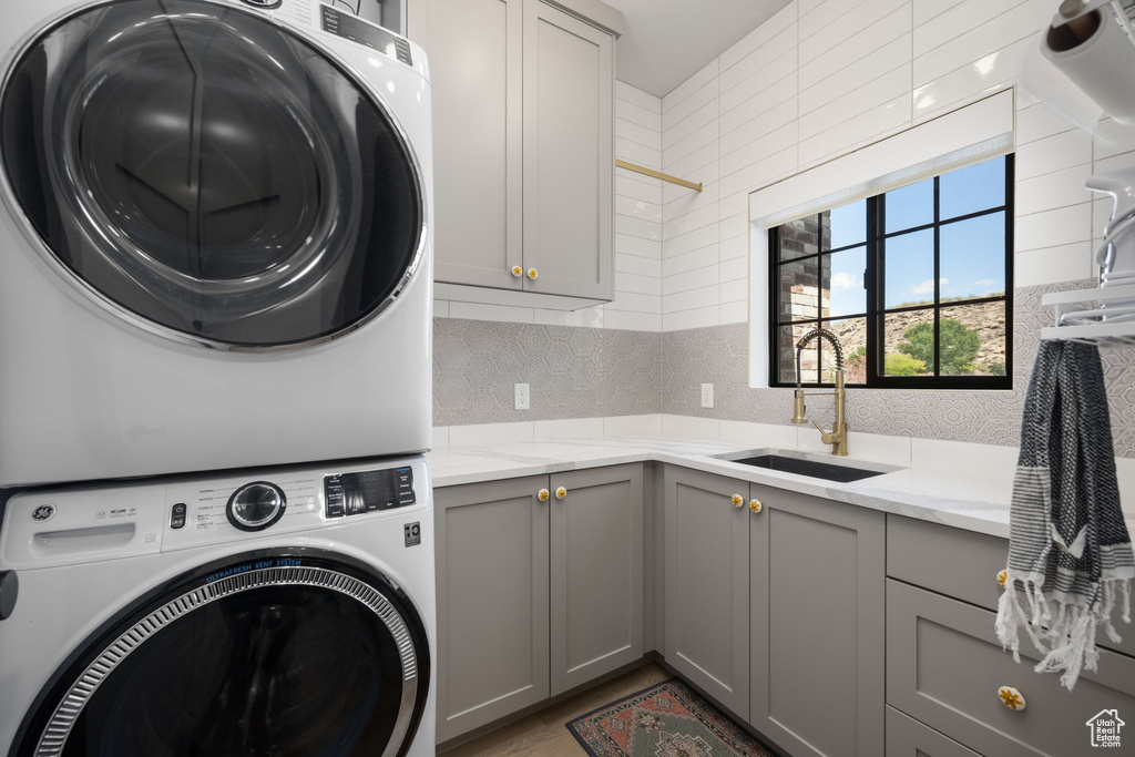 Laundry area with a sink, cabinet space, and stacked washer / drying machine