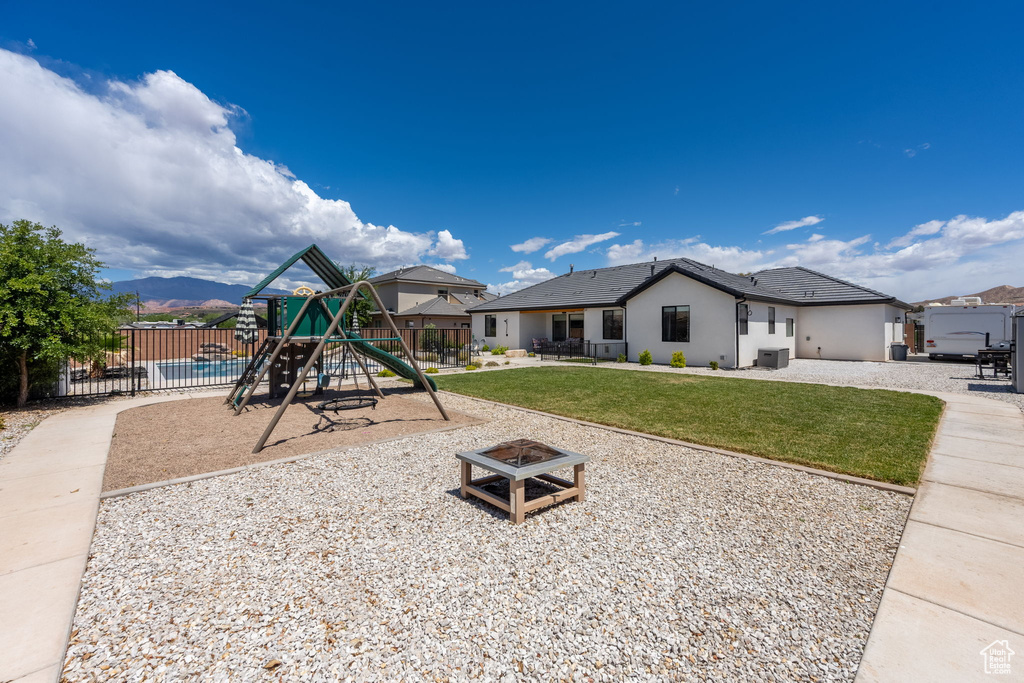 Communal playground featuring fence, a patio, a lawn, and an outdoor fire pit