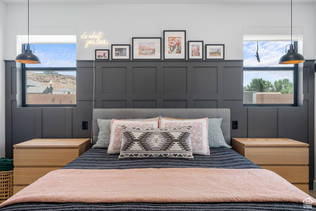 Bedroom featuring wainscoting, multiple windows, and a decorative wall