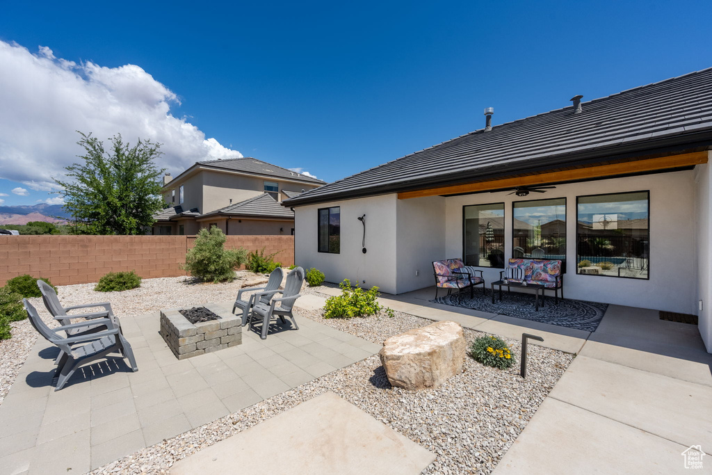 Back of property with an outdoor living space with a fire pit, fence, stucco siding, a ceiling fan, and a patio area