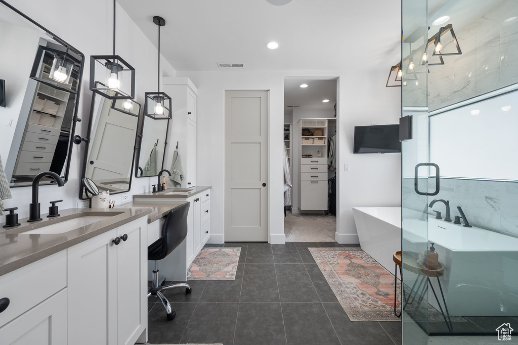 Full bath featuring a walk in closet, tile patterned flooring, a sink, a freestanding tub, and visible vents