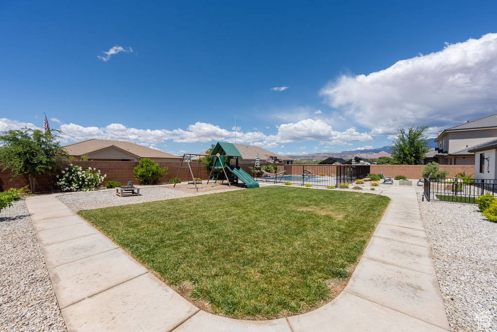 View of yard with a fenced in pool, a fenced backyard, and a playground