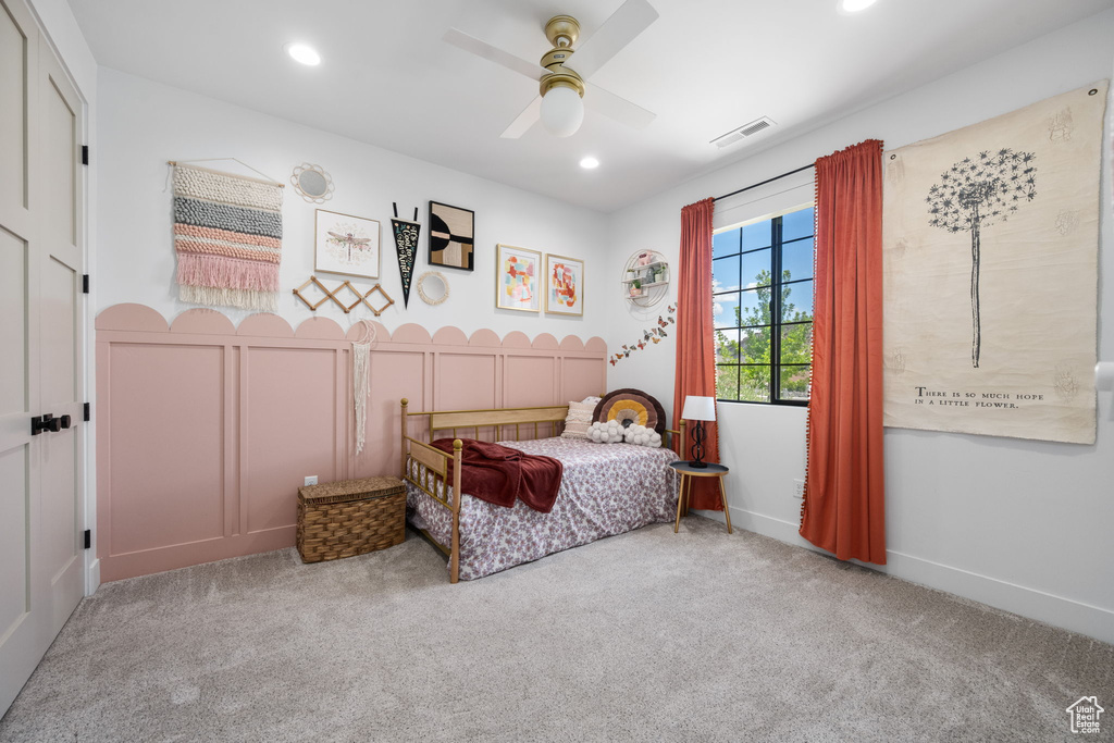 Carpeted bedroom with visible vents, recessed lighting, ceiling fan, and a decorative wall