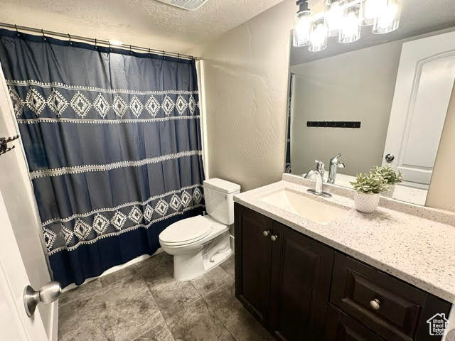 Full bathroom featuring toilet, a textured ceiling, a shower with curtain, and vanity