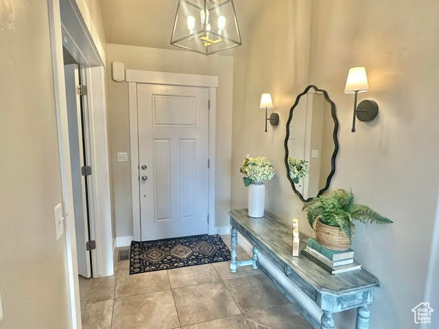 Entryway featuring baseboards, light tile patterned flooring, and a chandelier