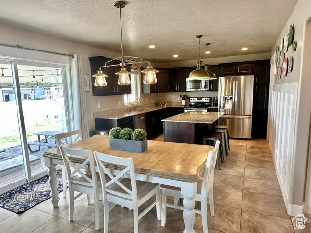 Kitchen with a textured ceiling, appliances with stainless steel finishes, a healthy amount of sunlight, and a center island