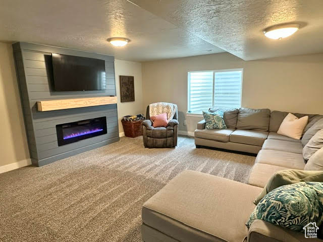 Living room featuring carpet flooring, a textured ceiling, and baseboards