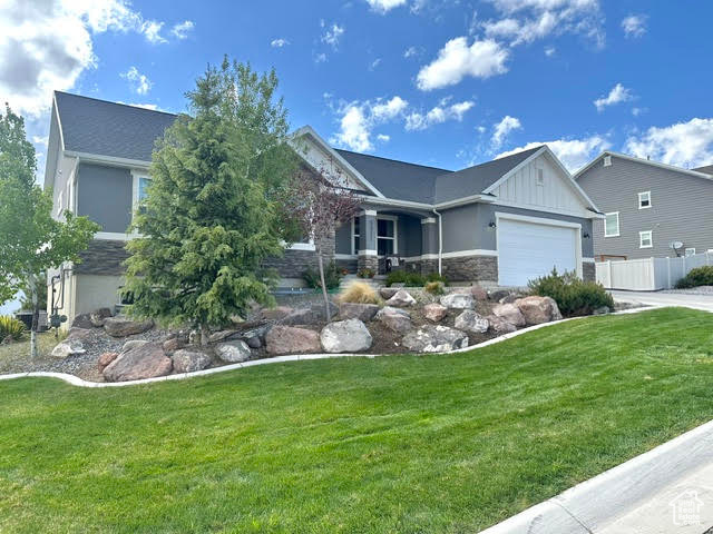 Ranch-style house with a garage, stone siding, driveway, and a front yard