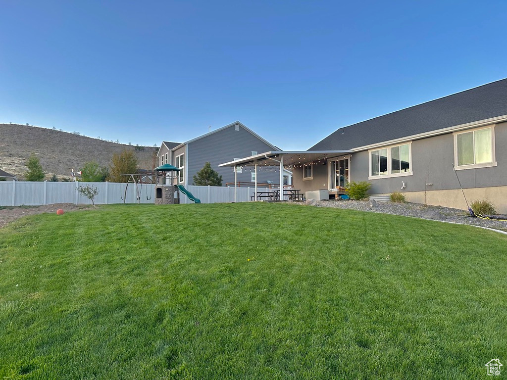View of yard with a playground and fence