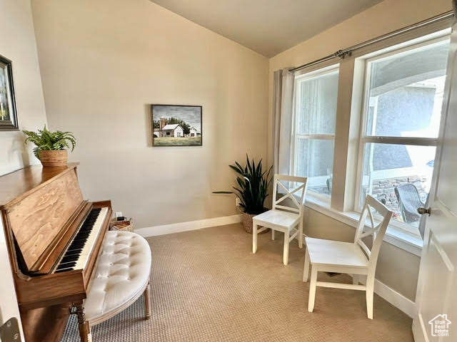 Sitting room featuring baseboards, plenty of natural light, carpet flooring, and lofted ceiling