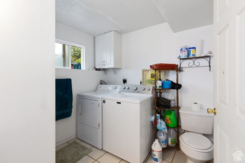 Washroom featuring light tile patterned floors, laundry area, washer and clothes dryer, and a textured ceiling