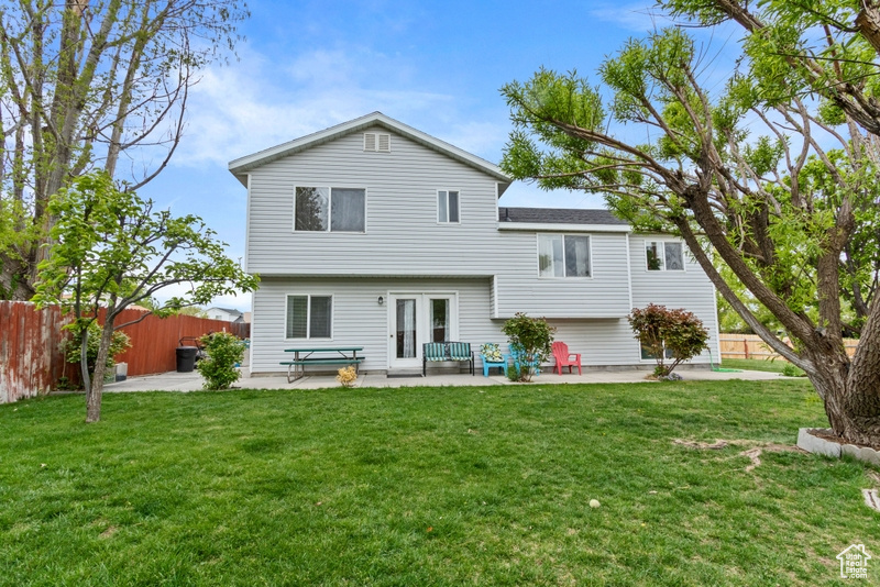 Rear view of house featuring a lawn, fence, and a patio area