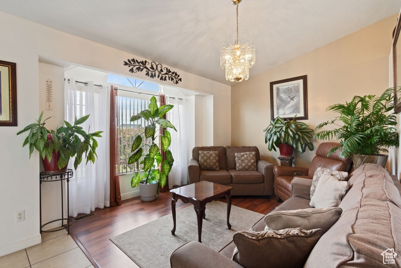 Living room featuring baseboards, a notable chandelier, and vaulted ceiling