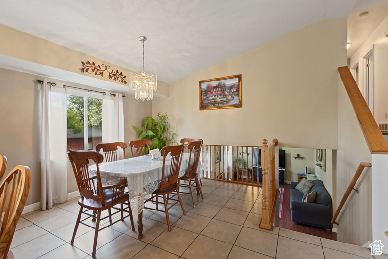 Dining area featuring tile patterned floors, a chandelier, baseboards, and lofted ceiling
