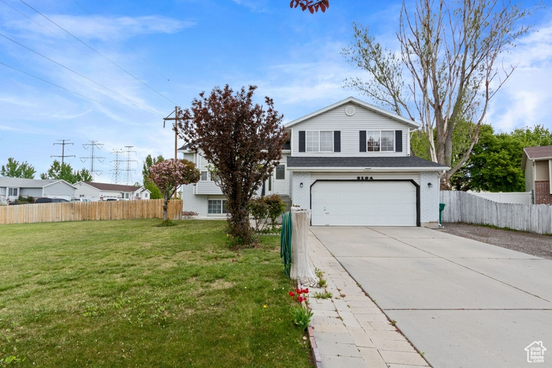 Traditional-style house featuring a garage, a front lawn, fence, and driveway