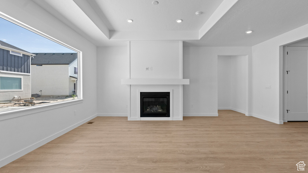 Unfurnished living room featuring recessed lighting, a large fireplace, baseboards, and light wood-type flooring