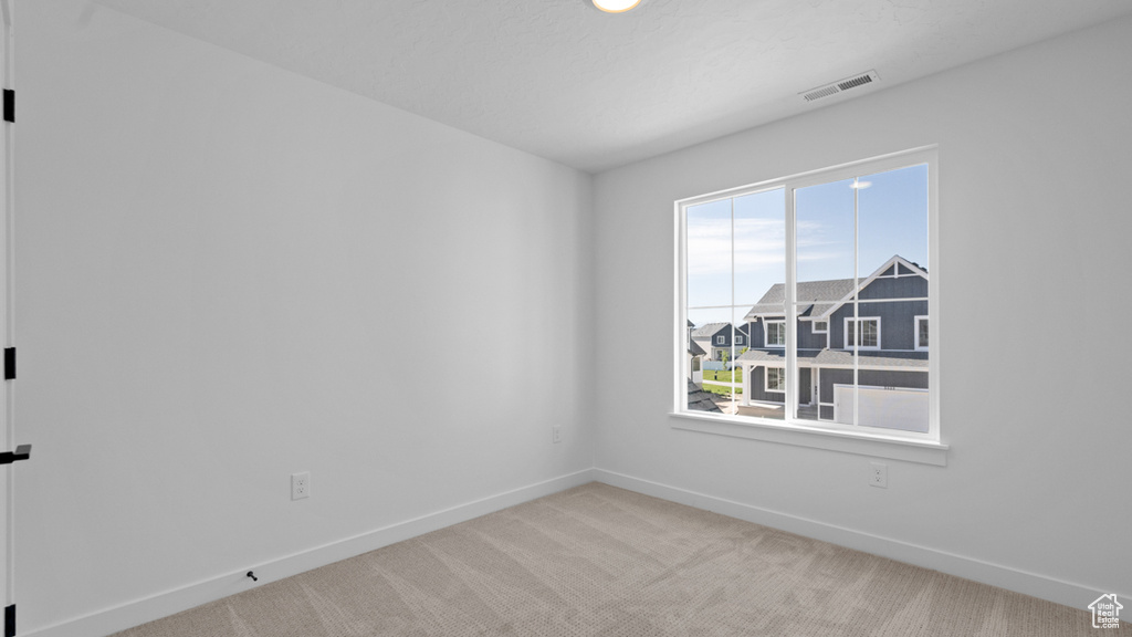 Empty room with visible vents, carpet flooring, and baseboards