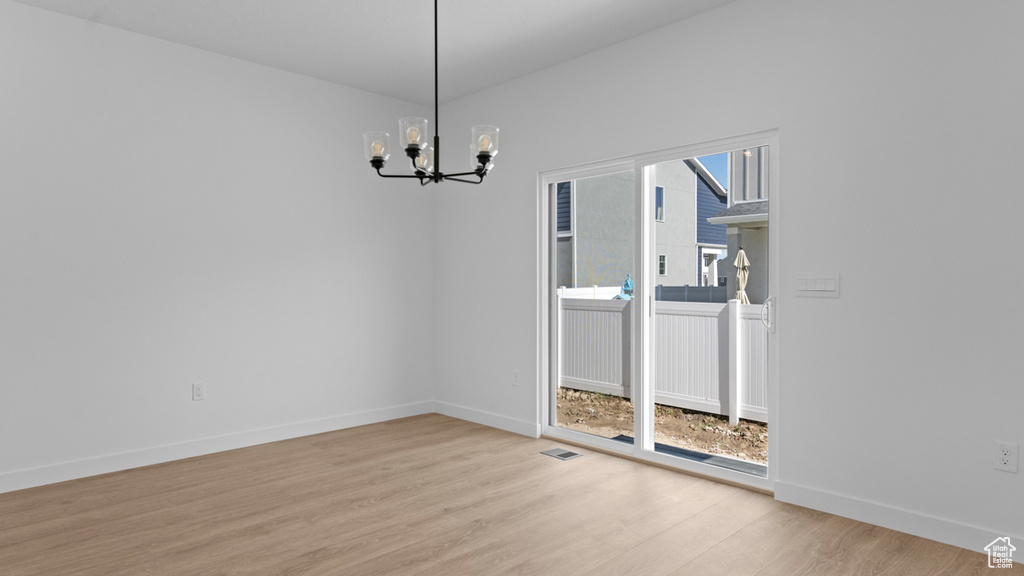 Unfurnished dining area featuring visible vents, baseboards, an inviting chandelier, and light wood finished floors
