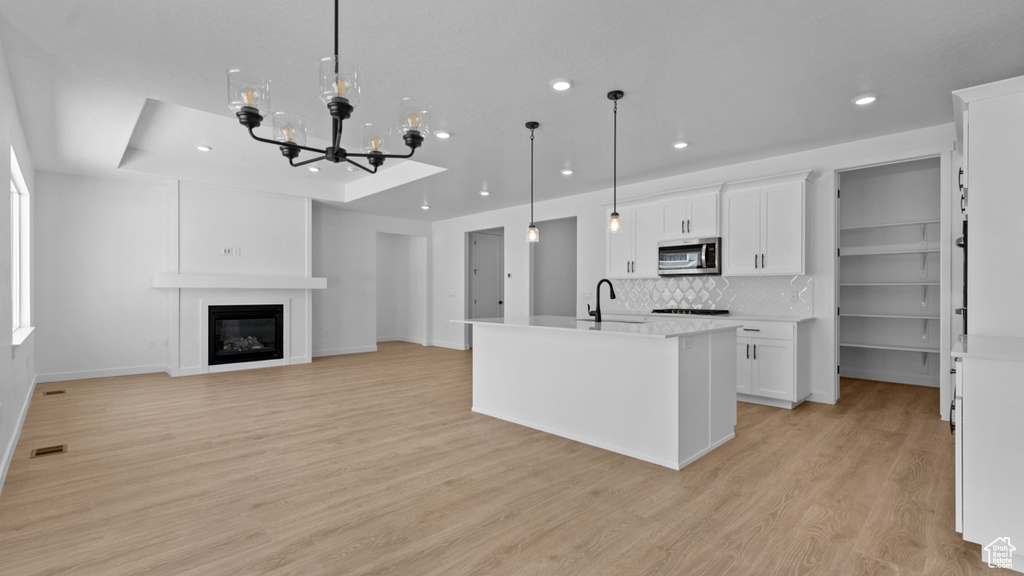 Kitchen with visible vents, a sink, light countertops, white cabinets, and stainless steel microwave