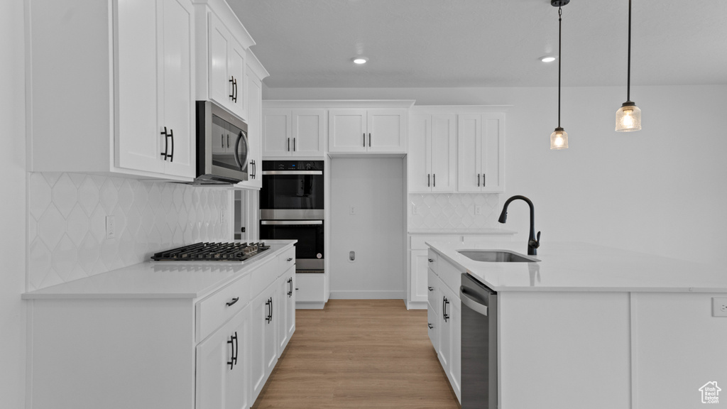 Kitchen featuring a sink, light countertops, backsplash, and stainless steel appliances