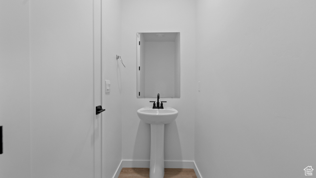Bathroom featuring baseboards, a sink, and wood finished floors