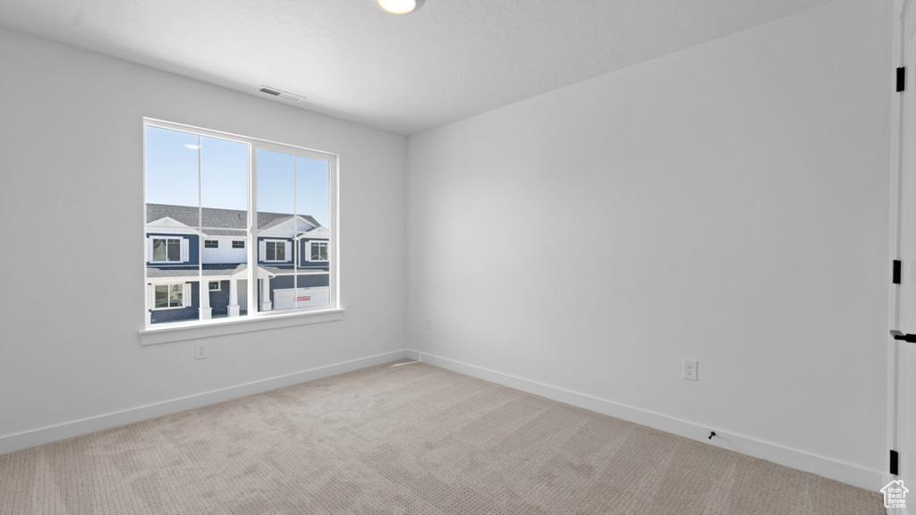 Unfurnished room with carpet floors, baseboards, and visible vents