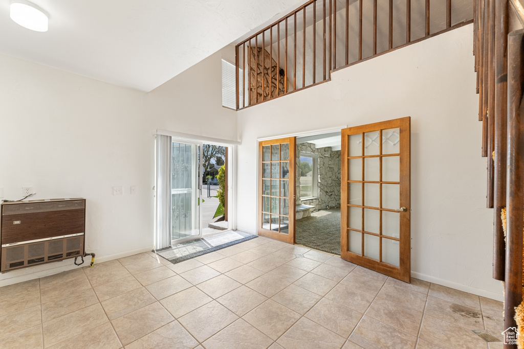 Entryway featuring baseboards, tile patterned flooring, and a towering ceiling