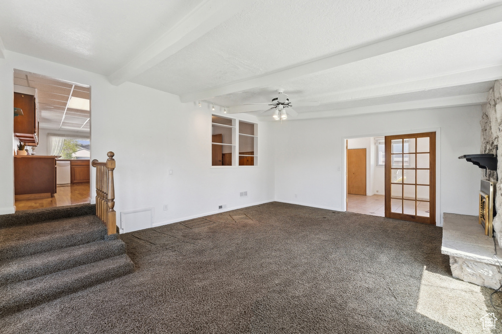 Unfurnished living room with stairs, carpet, ceiling fan, and beam ceiling