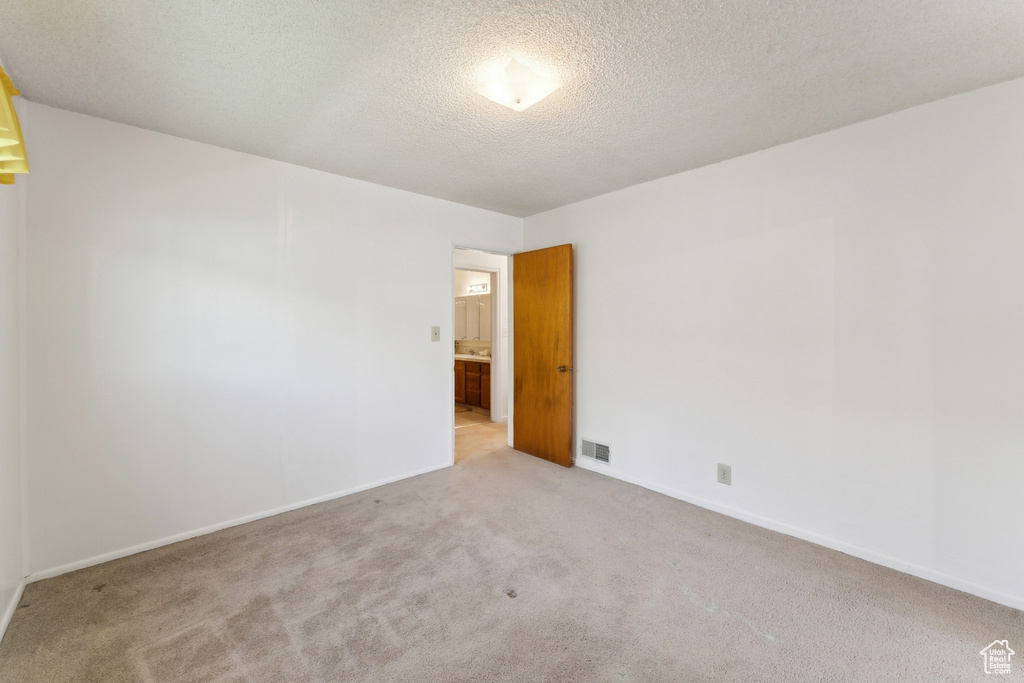Unfurnished room with baseboards, a textured ceiling, carpet, and visible vents