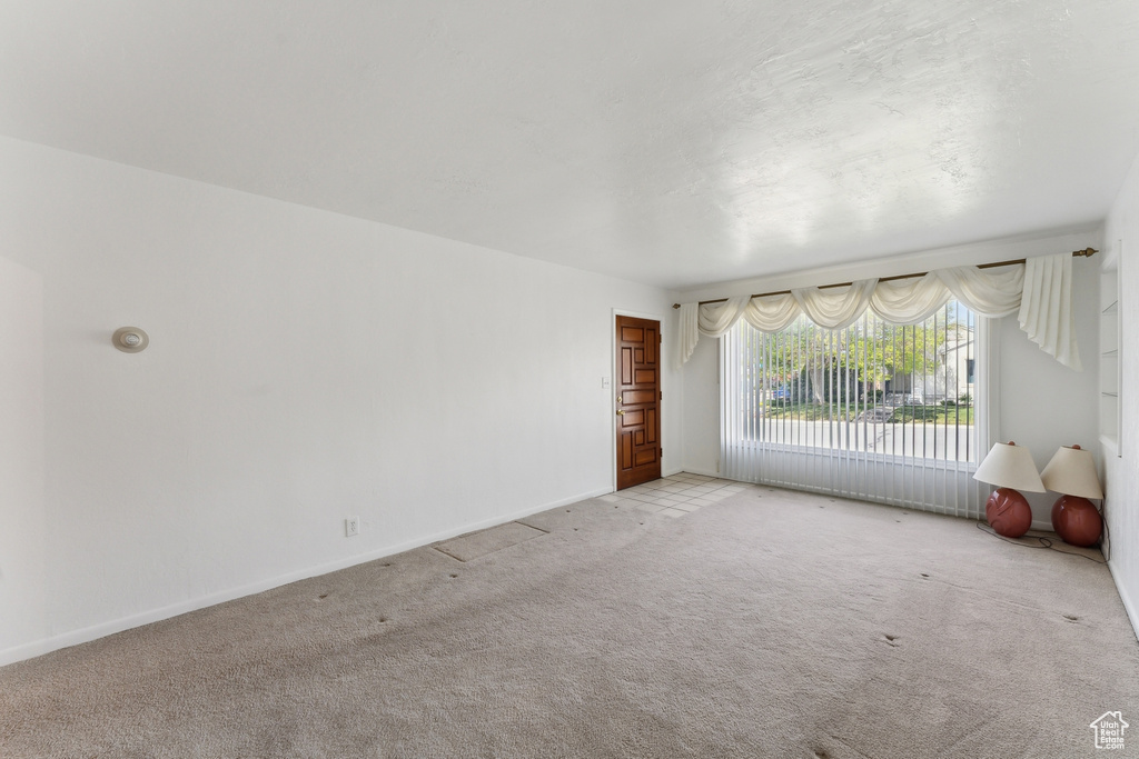 Unfurnished living room with baseboards and light colored carpet
