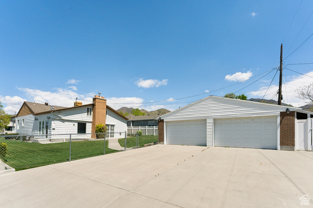 Ranch-style home with a front yard, a detached garage, brick siding, fence, and an outdoor structure