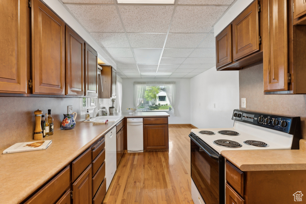 Kitchen featuring electric range, white dishwasher, light countertops, light wood finished floors, and a drop ceiling