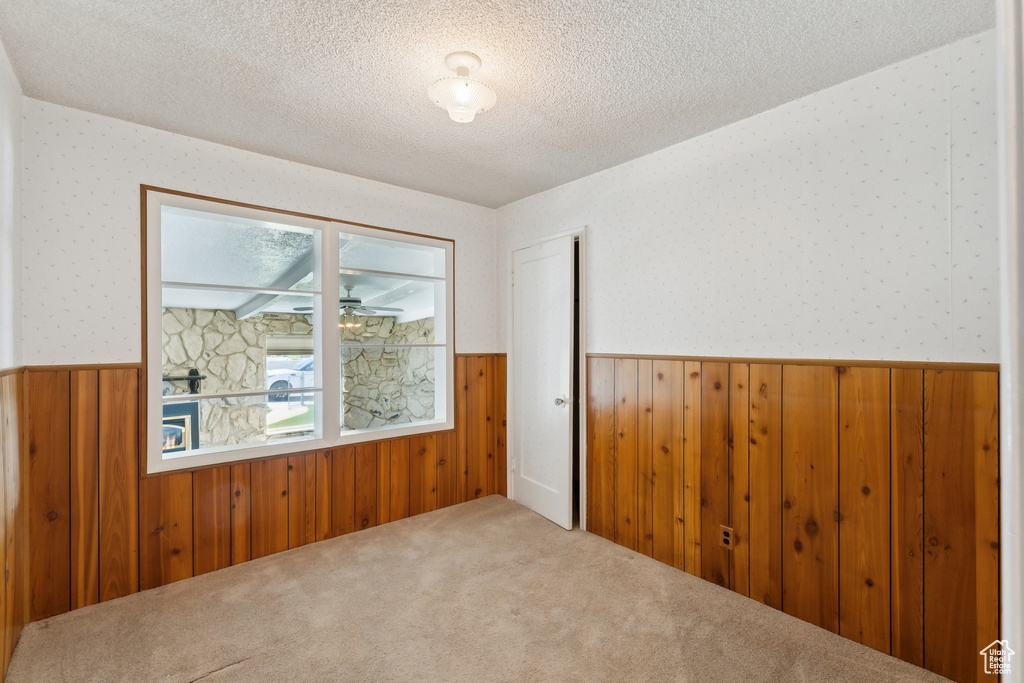 Unfurnished room featuring a textured ceiling, wood walls, and a wainscoted wall