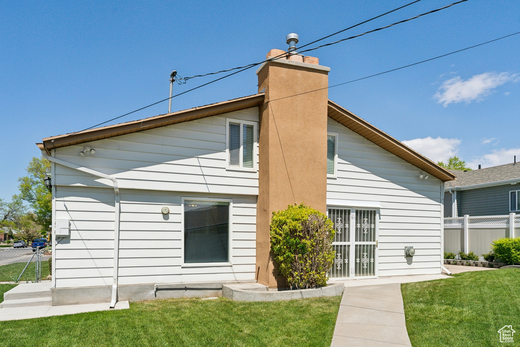 Back of house with fence, a yard, and a chimney
