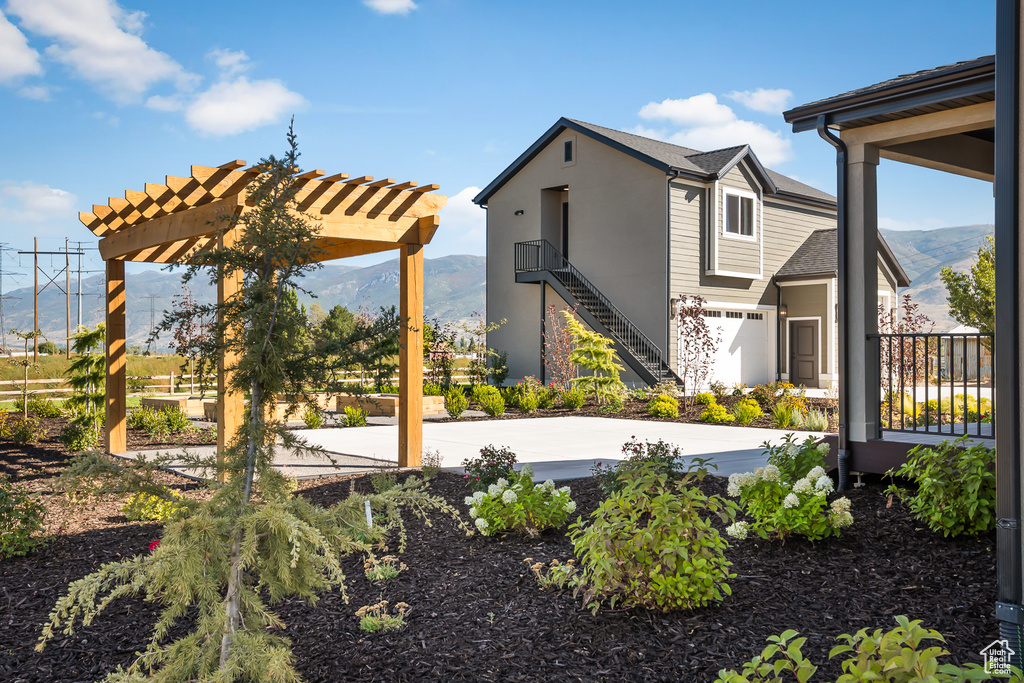 Exterior space featuring a pergola, a mountain view, stairs, and stucco siding