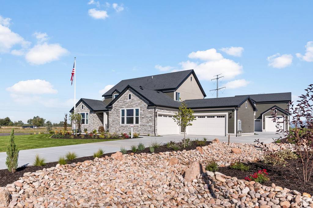 View of front facade with a garage, stone siding, and concrete driveway